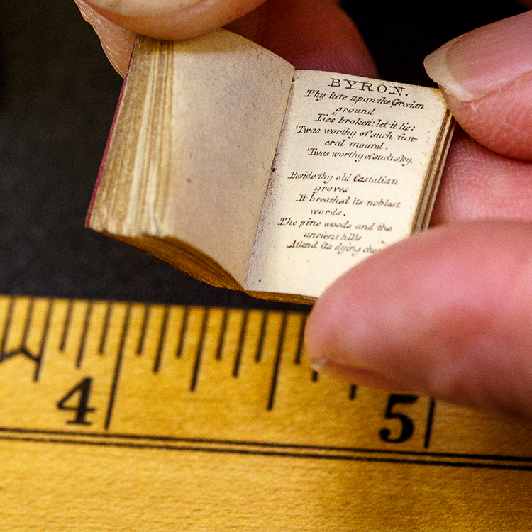 Small book opened to a page of Lord Byron being held over ruler
