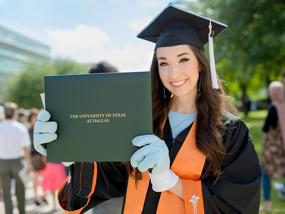 Molly Millsap holding up her mortarboard with her Temoc gloves
