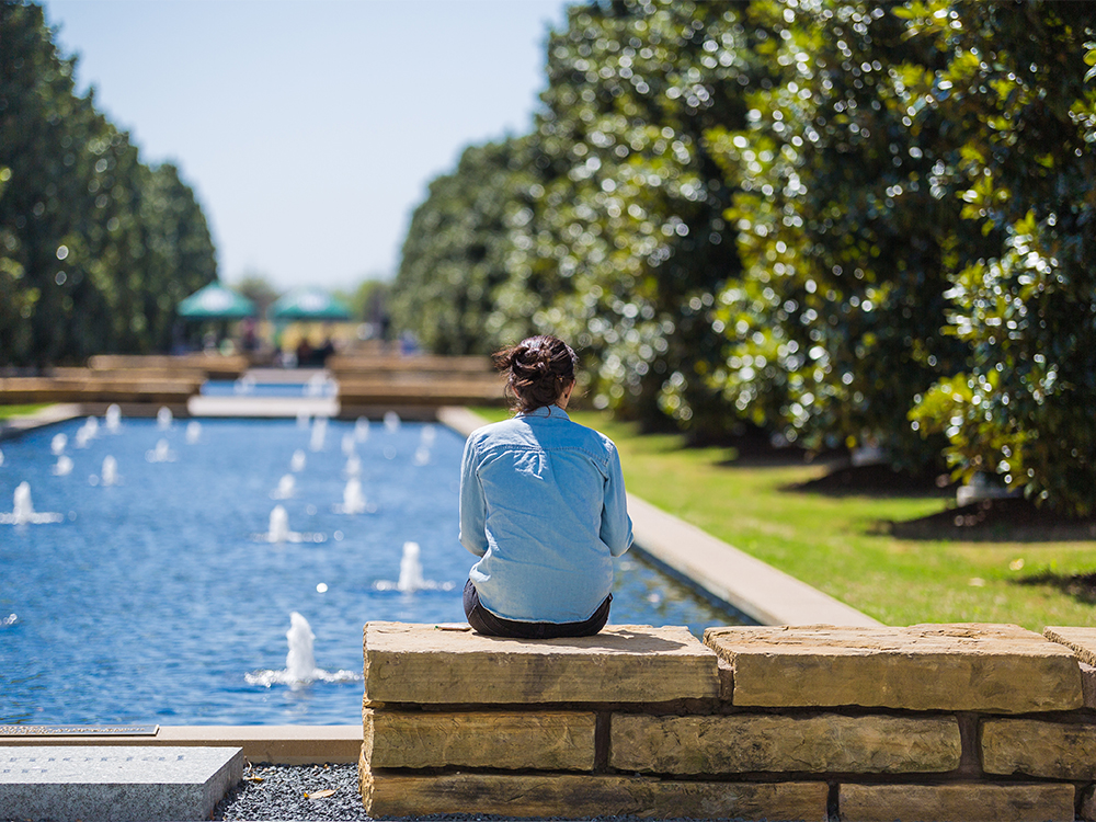 Woman sitting on stone slap by reflecting pools