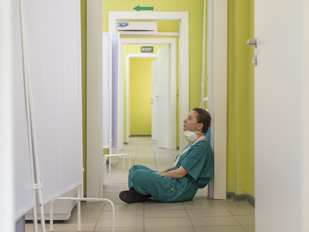 A nurse sits alone in a deserted hallway.