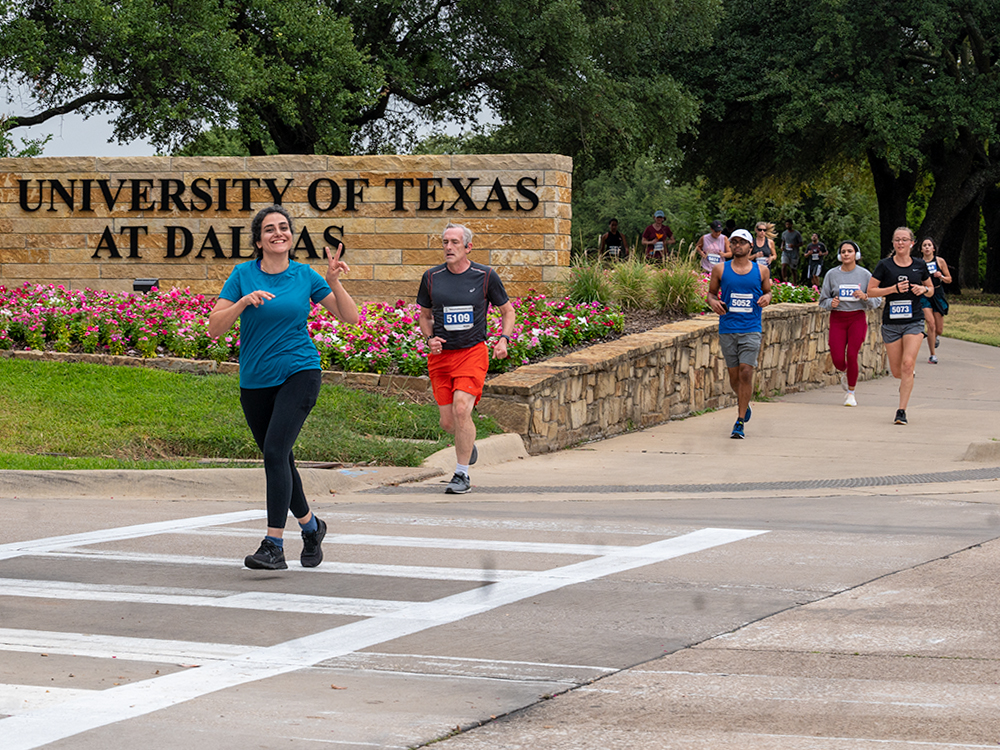 Runners go past a campus entrance sign during the race