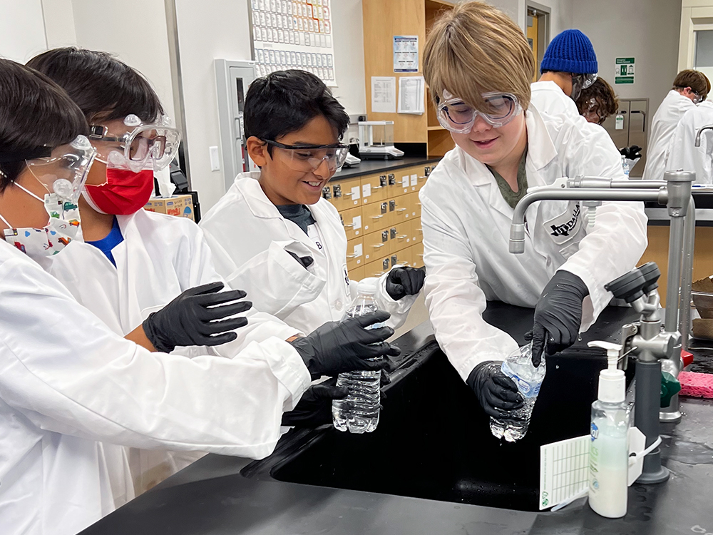 Young students stand over a lab sink to do an experiment