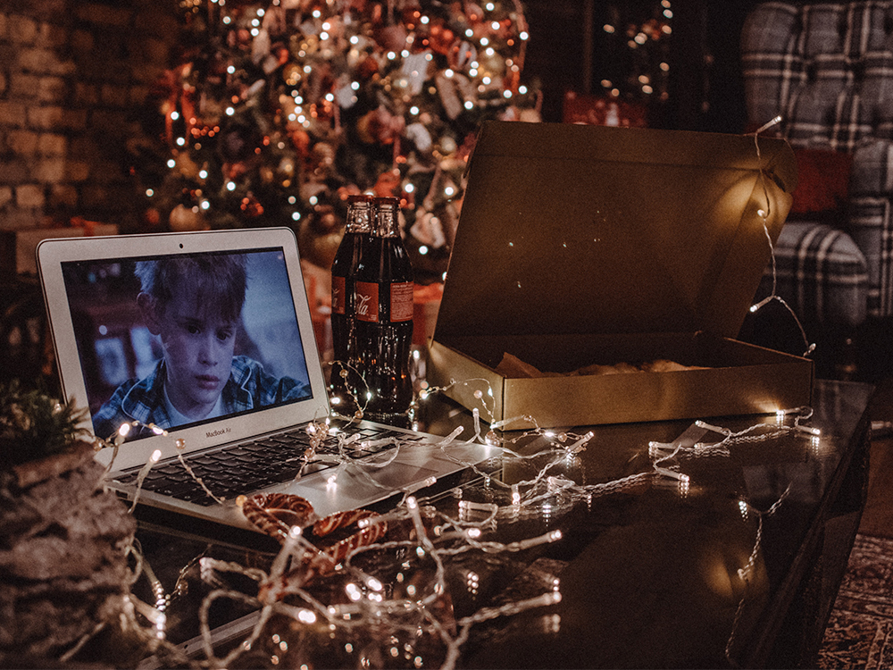 The movie "Home Alone" plays on a laptop surrounded by holiday lights and other decorations being put up.