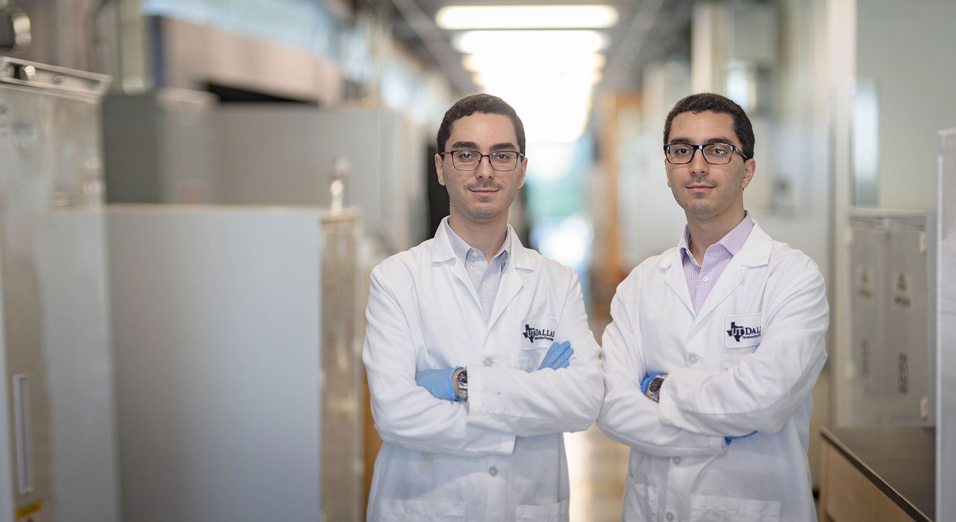 Parsa and Pouya Modareszadeh standing together with arms crossed, wearing lab coats.