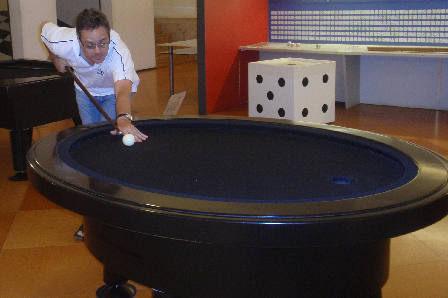 Dr. Vladimir Dragovic lines up a shot on a black felt elliptical billiards table