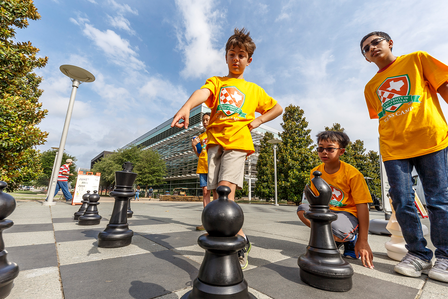 Children play a game of chess with giant pieces on an outdoor chessboard on the campus of The University of Texas at Dallas.